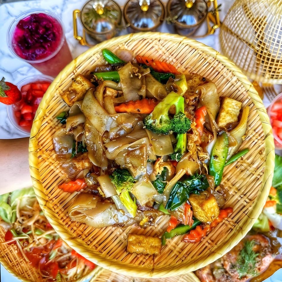 So Saap's Pad See Ew with wide noodles, broccoli, carrots, and tofu in a woven basket.
