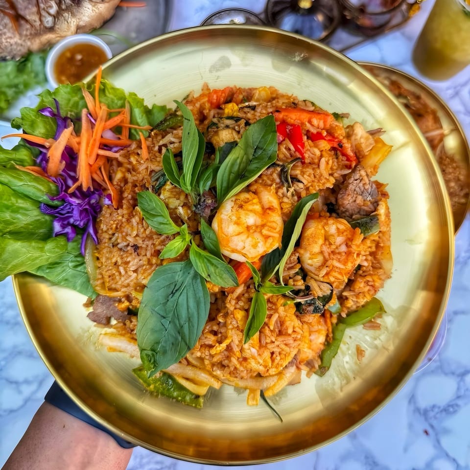 So Saap's Thai fried rice with shrimp, vegetables, and basil on a golden plate.